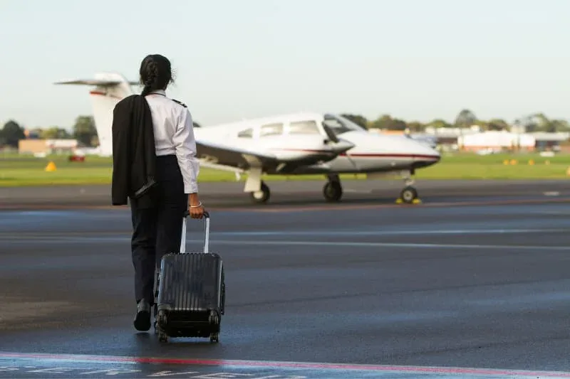 Pilot walking toward aircraft with luggage, representing aviation professionals who need effective recovery methods between flights.