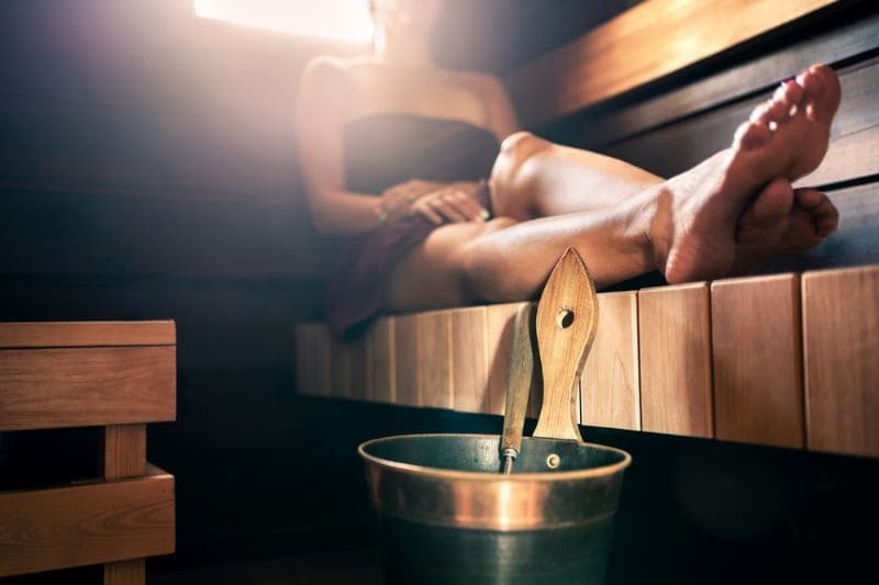 A tranquil setting inside a sauna room with a woman seated comfortably, highlighting the ideal duration for wellness and heat therapy without overexposure.