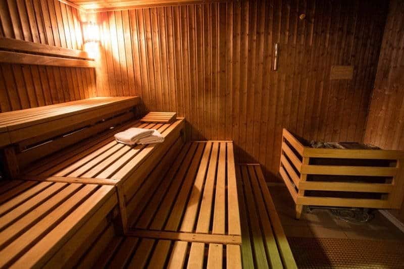 Classic wooden sauna room with benches and rolled towels, evoking the timeless appeal of traditional saunas.