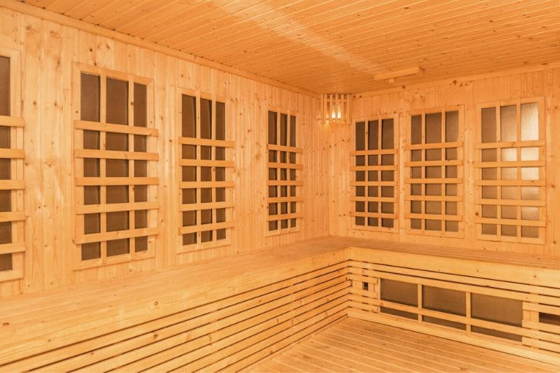 Spacious wooden infrared sauna interior with multiple heating panels, demonstrating how to use infrared sauna for effective heat therapy and relaxation.