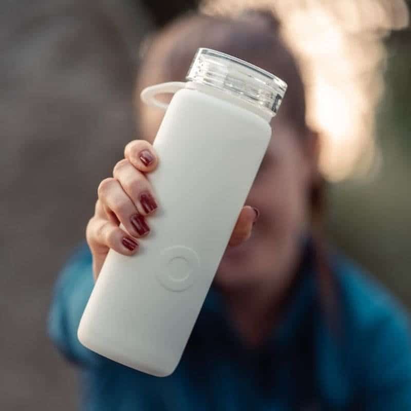 A female holding a white water bottle, emphasizing the importance of staying hydrated while using an infrared sauna for health and wellness.