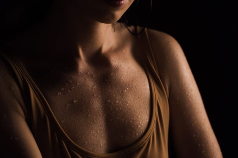 Close-up view of a person's upper chest area with moisture droplets, exemplifying the sweating process during a rejuvenating sauna session, ideal for relaxation and detoxification.