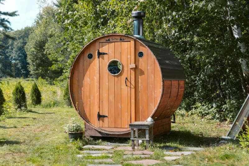 A quaint barrel sauna nestled outdoors amongst lush greenery, symbolizing a natural approach to health and wellness.
