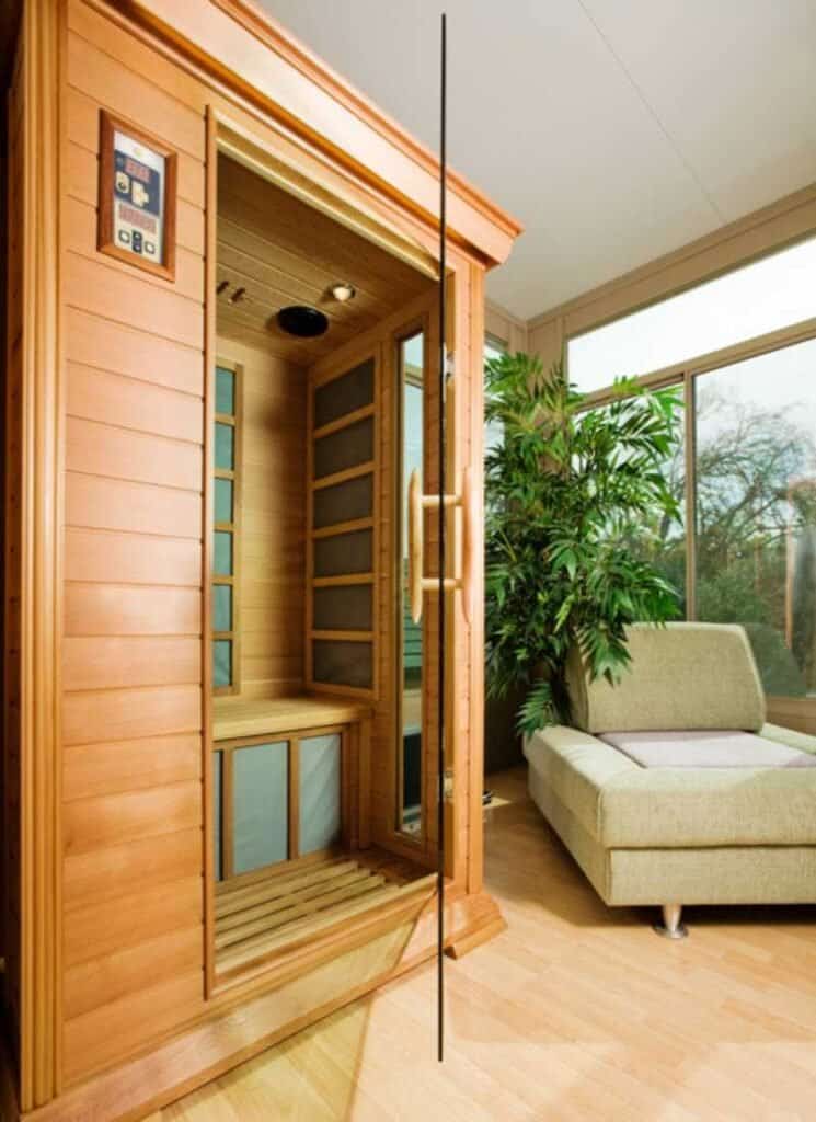 A modern indoor sauna with glass door open, revealing the wooden interior, providing a serene and private relaxation experience
