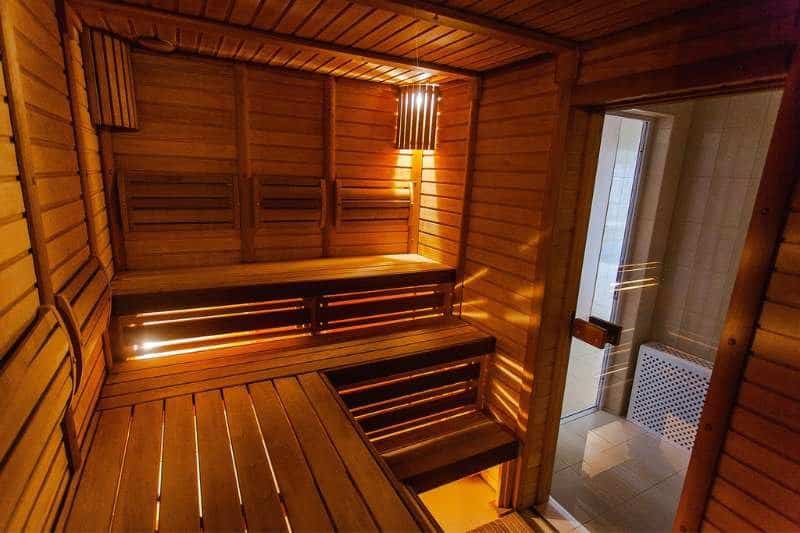 The warm glow of a sauna room in the evening, featuring wooden benches and soft lighting, offering a cozy and inviting space for relaxation away from moisture.