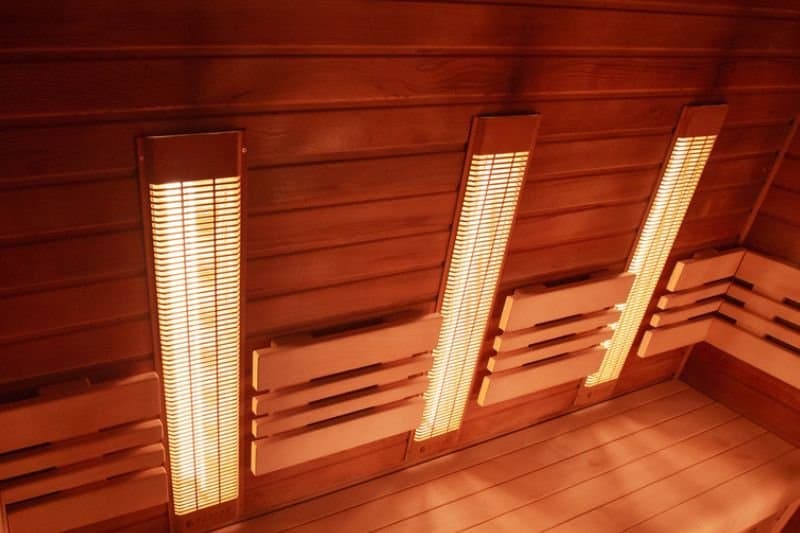 Interior view of an infrared sauna with vertical glowing heat panels, providing a tranquil and therapeutic atmosphere.