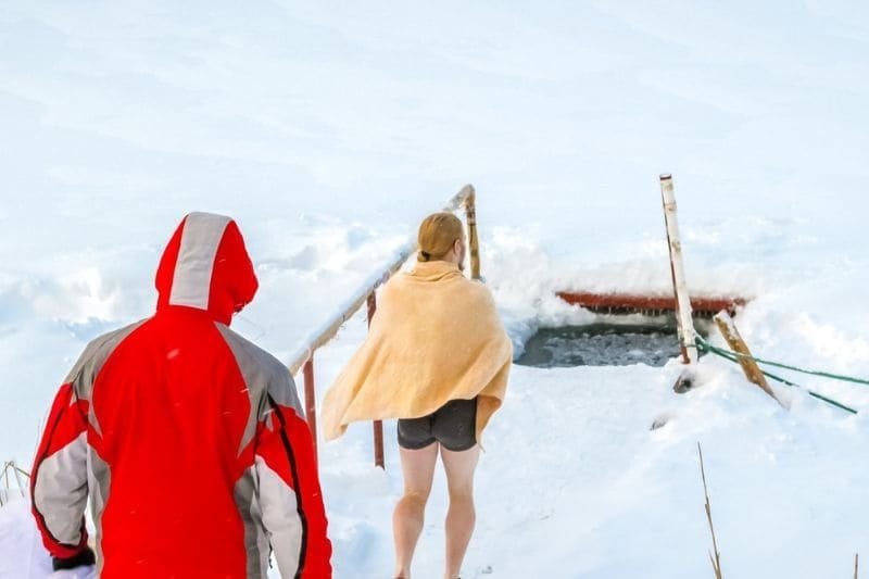 Individuals preparing for an ice bath in the snow, with focus on health benefits of cold exposure therapy.