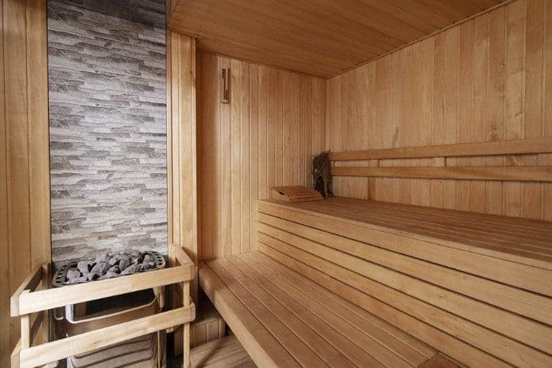 Interior of a traditional wooden sauna with electric heater and stones, emphasizing relaxation and heat therapy benefits.