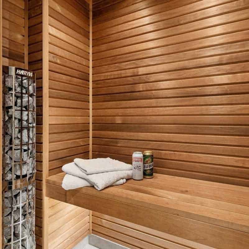 An inviting sauna room with neatly stacked towels and sauna stones, showcasing the serene and clean atmosphere of a wooden dry sauna setup.