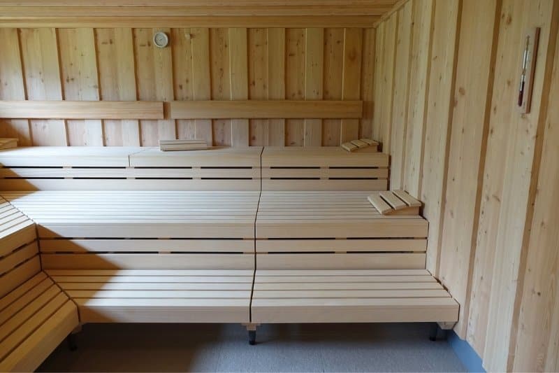 Interior of a modern sauna with wooden benches, highlighting the clean and serene environment for relaxation and detoxification.