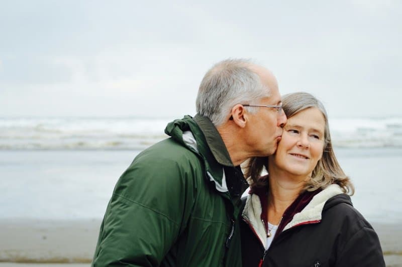 Senior couple enjoying on a beach , looking refreshed showcasing the anti-aging skin benefits of infrared sauna