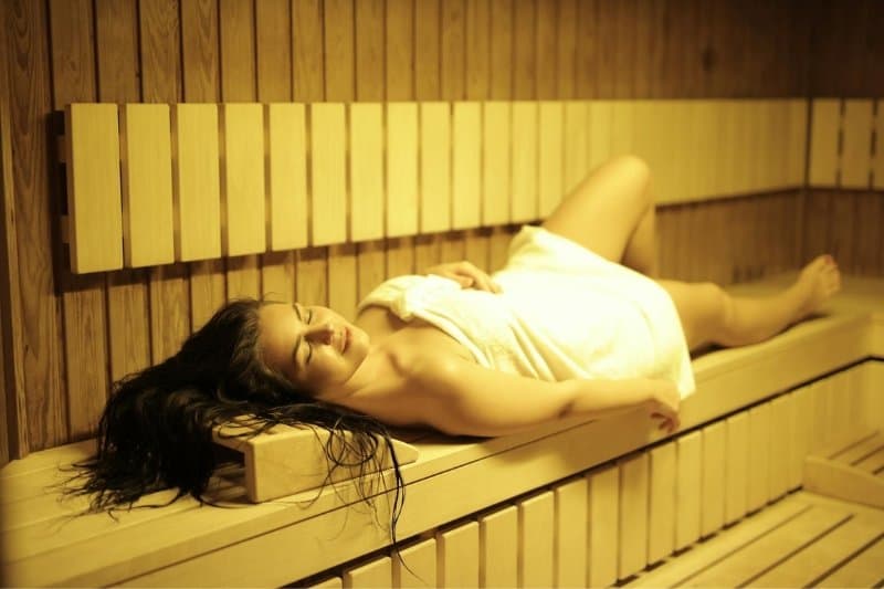 Woman relaxing in a sauna, showcasing infrared sauna benefits for skin health and stress relief.