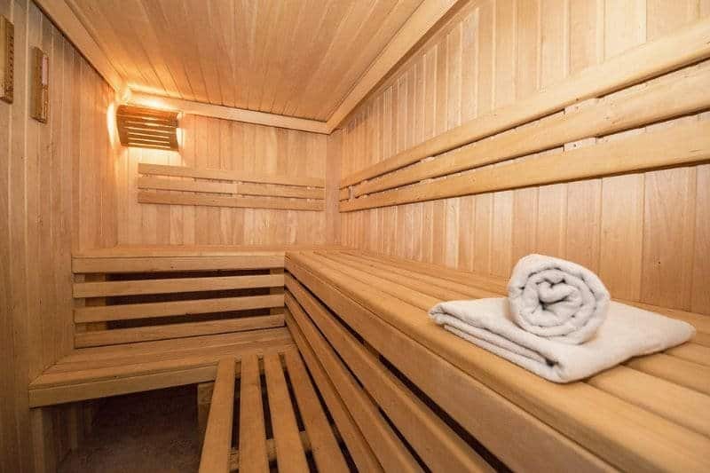 Interior view of a traditional wooden sauna with benches and rolled towel.