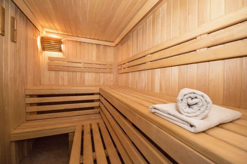 Cozy wooden sauna interior with multi-level benches and a white towel, highlighting a traditional electric heater.