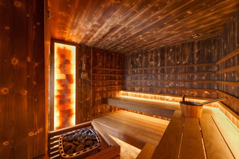 Warm and inviting home sauna with glowing wooden panels and electric heater.