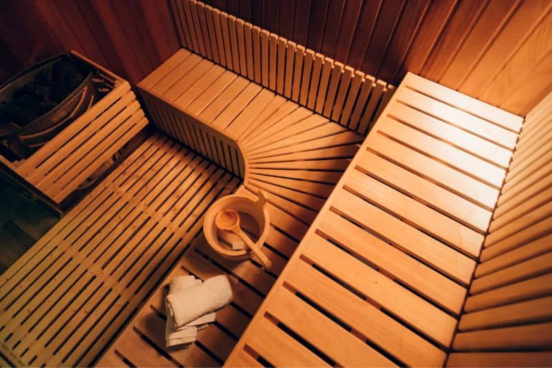Contemporary home sauna interior design with sleek wooden benches and ladle.