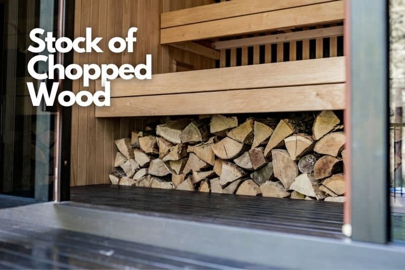 Stacked firewood neatly arranged under a wooden shelter, to be used as source of heat in a sauna.