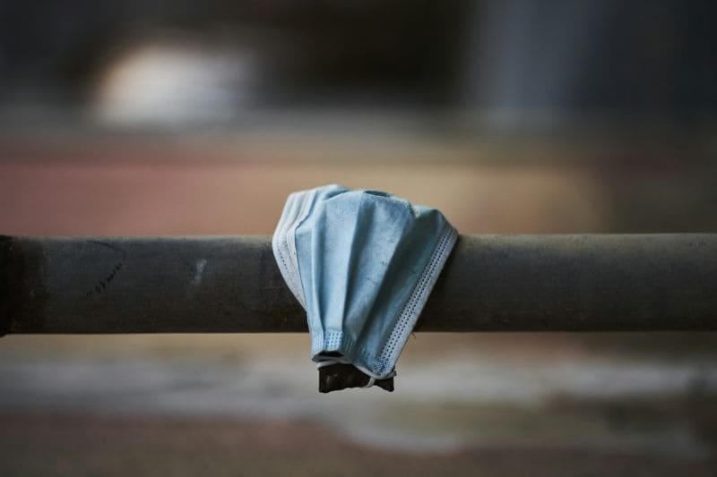Abandoned face mask on a metal railing, representing the return to wellness routines with infrared saunas in the post-pandemic era.