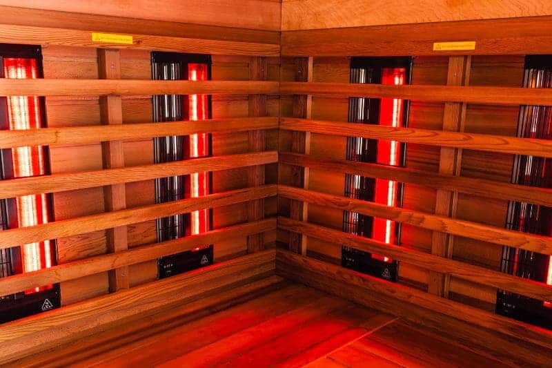 Inside view of an infrared sauna cabin used for treating inflammation, showcasing the glowing red heat elements.