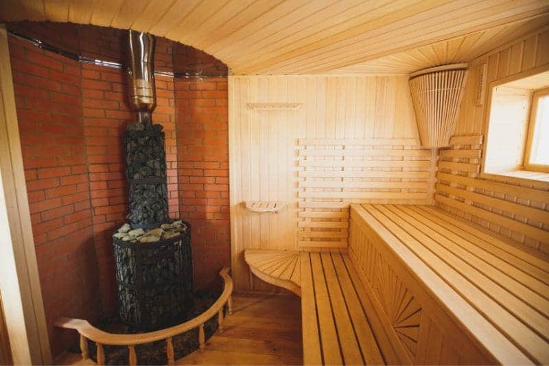 Interior of a traditional wood-burning sauna with a rustic stone heater, evoking the authentic sauna atmosphere.