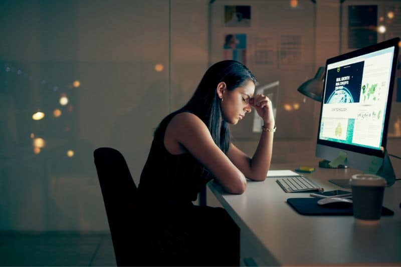 Young businesswoman looking stressed while using a computer at night in her office.