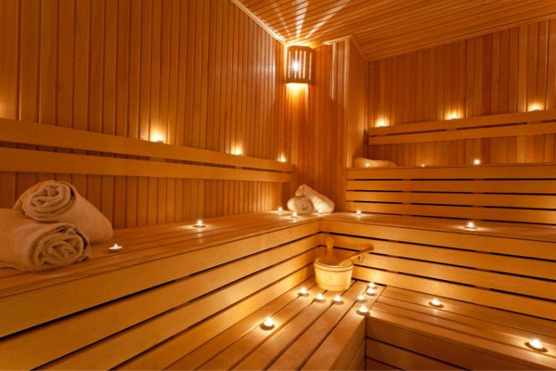 A modern wooden sauna with a softly lit interior. The benches are adorned with rolled towels, enhancing the calm and relaxing atmosphere.