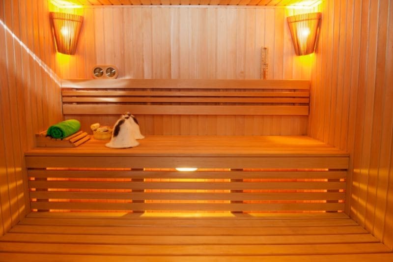 An empty sauna with a clean wooden interior, featuring towels and sauna accessories neatly placed on a bench.