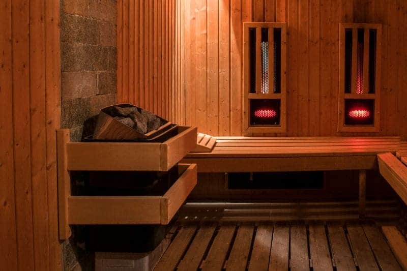Sauna room combining infrared heating panels and an electric sauna heater for a versatile sauna experience.