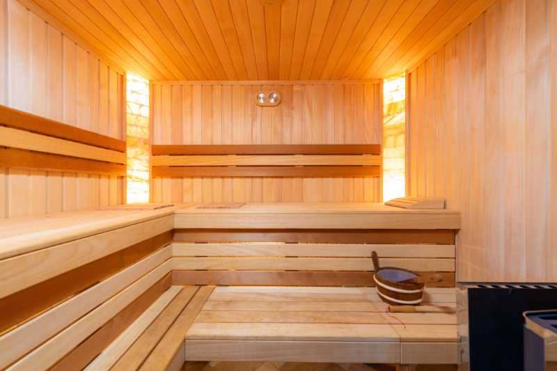 Interior view of a modern wooden sauna with spacious seating and ambient lighting, perfect for a relaxing sauna session.
