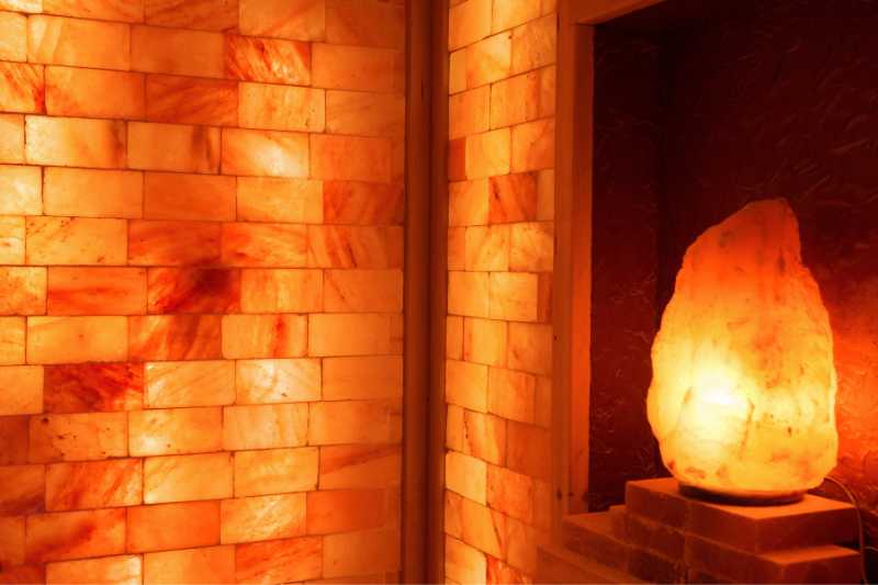 Himalayan salt lamp glowing warmly in a salt sauna, illustrating the ambient lighting and its calming effects.