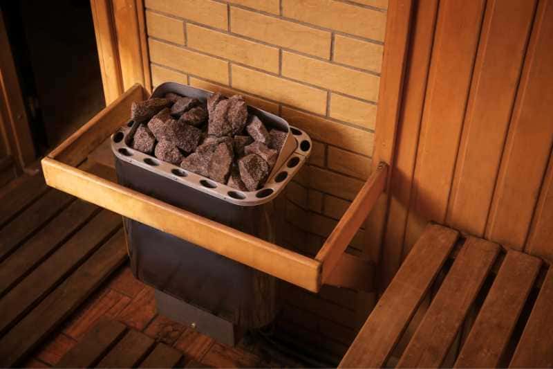 Close-up view of a sauna heater's stone compartment within a wooden sauna, emphasizing the quality and setup of the heating elements.