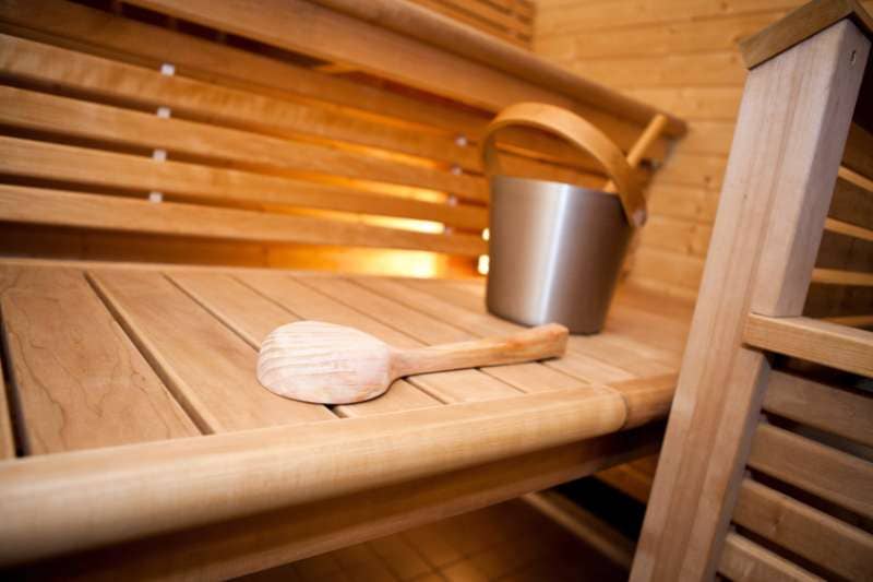 Detailed view of a sauna's wooden bench featuring a traditional sauna ladle and bucket, essentials for a genuine sauna experience.