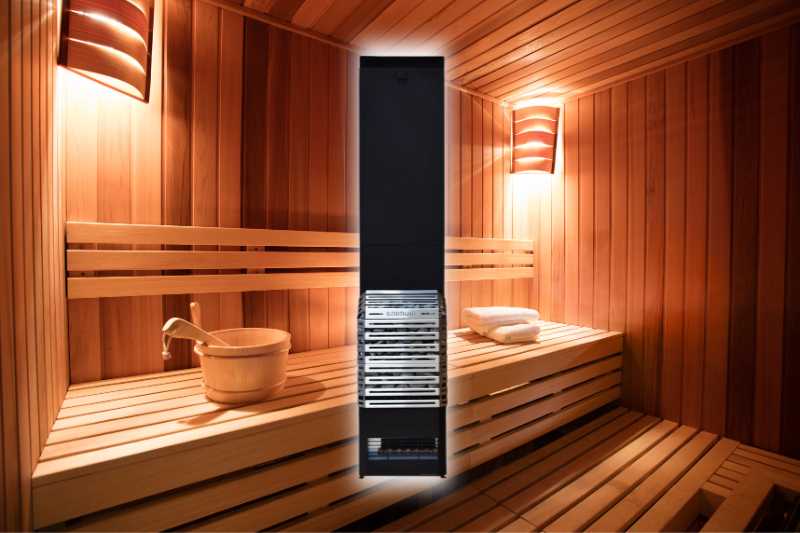 Saunum AIR 7 Electric sauna heater (stainless steel basket design) image with a modern sauna in the background with rich wooden paneling, wooden benches, and essential sauna accessories like a wooden bucket and ladle.
