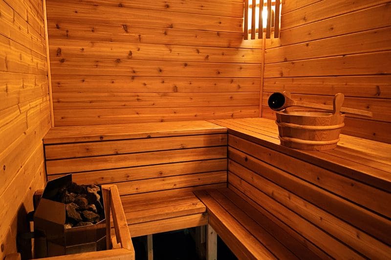 Cozy interior of a wooden sauna with built-in benches, an electric heater, and ambient lighting for a relaxing atmosphere.