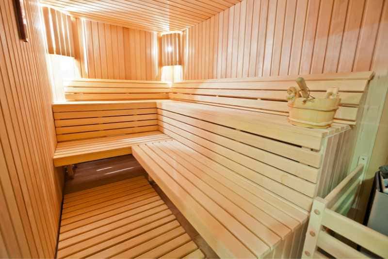 An empty modern sauna room with wooden benches and a bucket, ready for a rejuvenating sauna session.