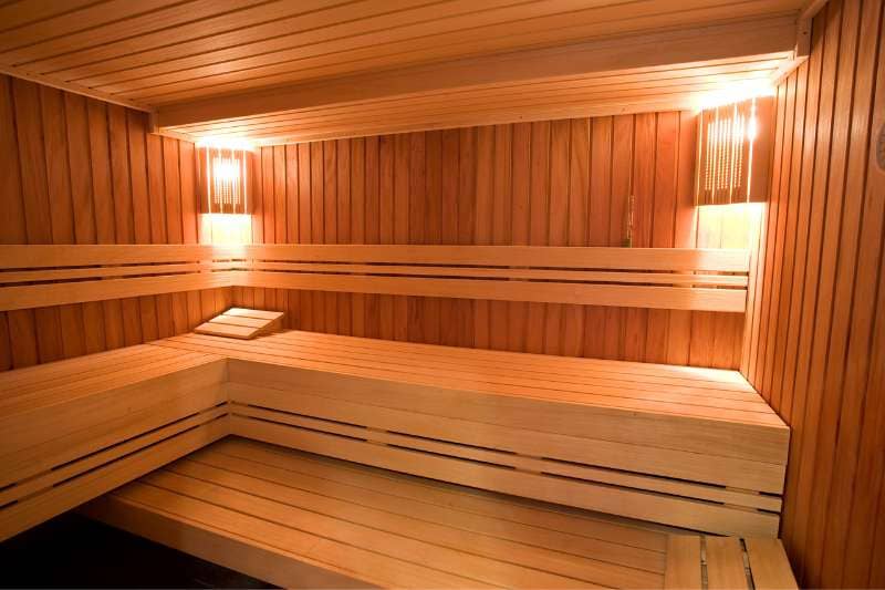 A modern sauna with light wood paneling and built-in lighting, featuring a clean and spacious interior.