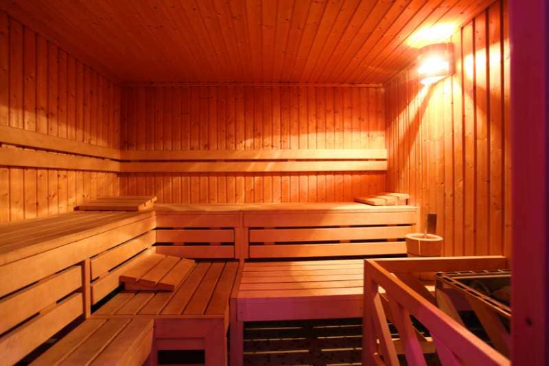 A spacious traditional sauna with wooden benches and a soft warm glow from the lighting.