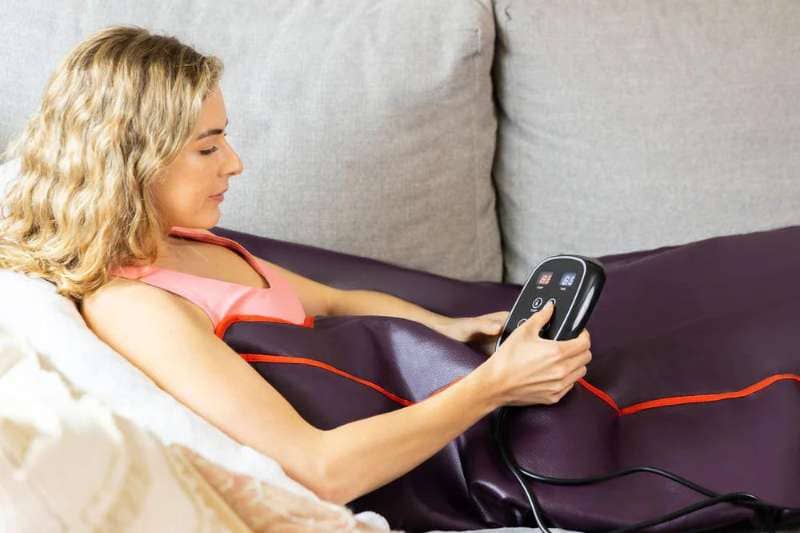 Woman Using Sun Home Sauna Blanket on Sofa with Digital Controller