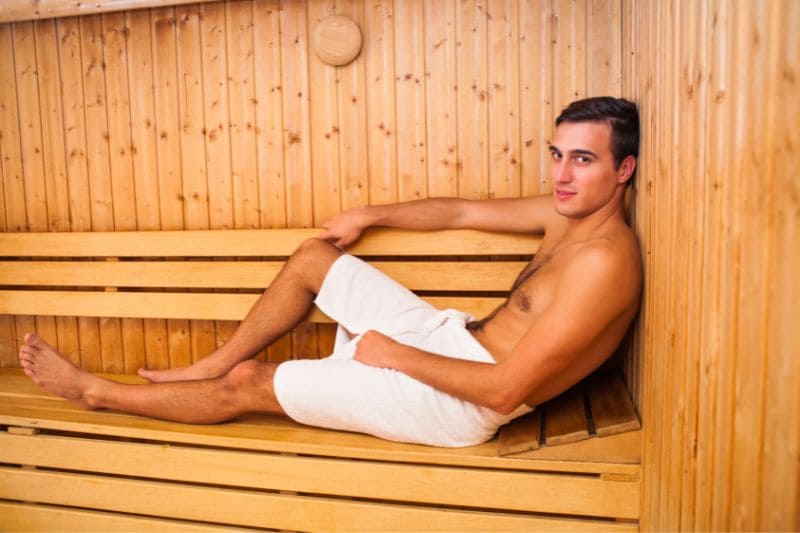 A man comfortably relaxing in a sauna, wrapped in a towel, enjoying the soothing heat.