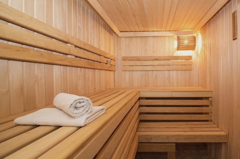 Minimalistic sauna interior with clean wooden benches, soft lighting, and a neatly folded towel on the bench.