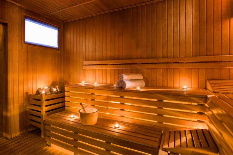 A cozy sauna setup with wooden benches, soft towels, and dim candlelight creating a relaxing atmosphere.