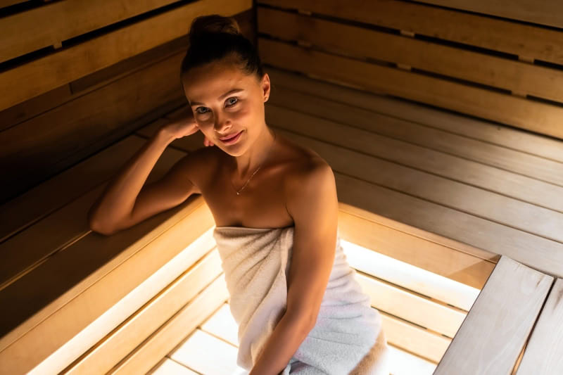 A happy woman smiles as she enjoys the therapeutic heat of a sauna.