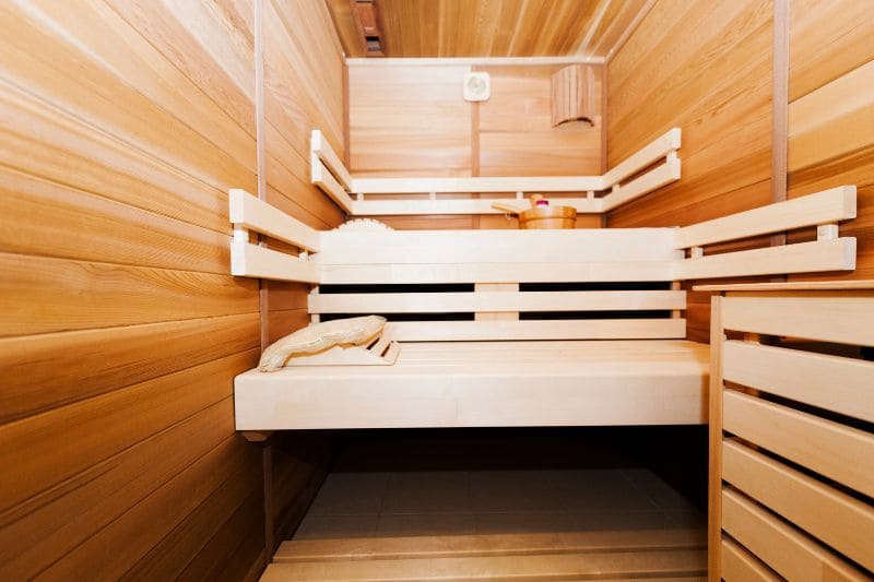 Compact sauna with efficient use of space, featuring tiered wooden seating and a light-colored cedar interior