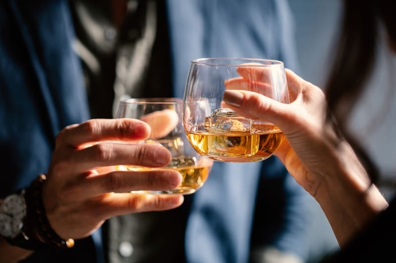 Two people cheersing with glasses of alcoholic drinks.