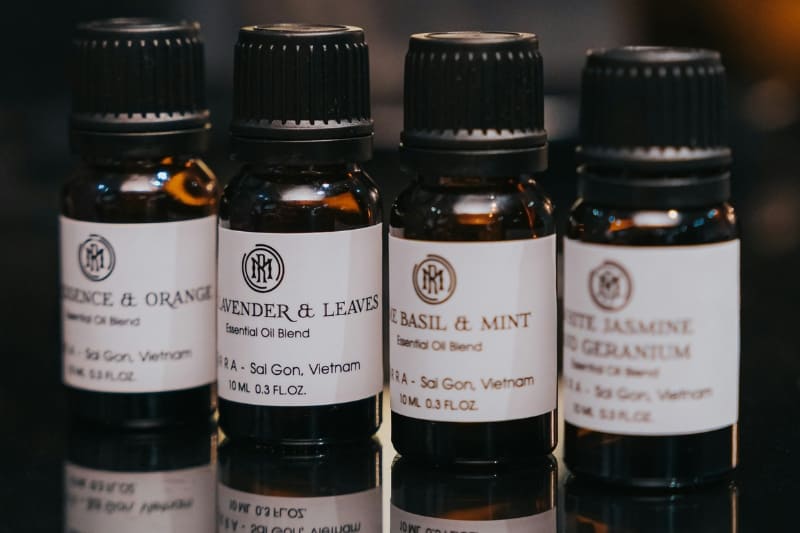 Four amber glass bottles of essential oil blends, including lavender, basil, and mint, for aromatherapy.