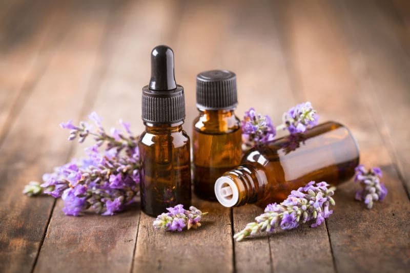 Brown glass bottles filled with lavender essential oil, surrounded by fresh lavender flowers, ideal for aromatherapy in sauna decor.