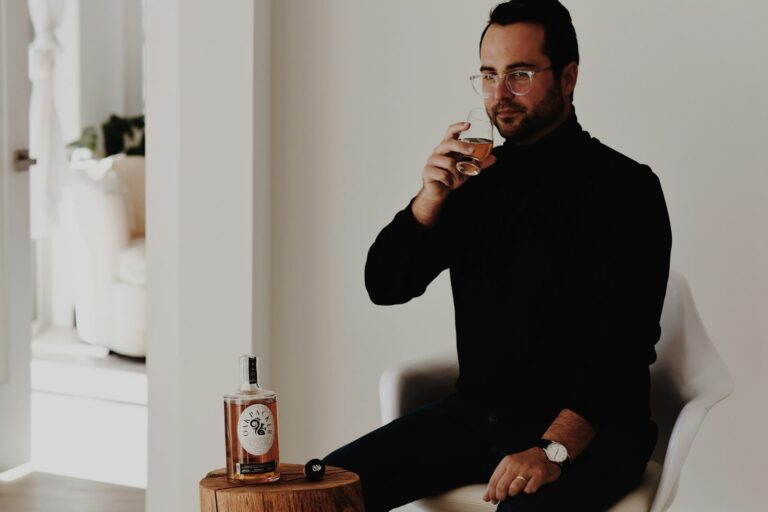 A man sits thoughtfully with a glass of whiskey, highlighting the consumption of alcohol that some believe can be "sweated out."