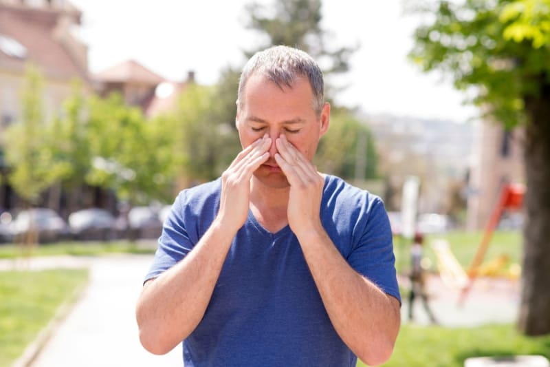 A man holding his nose, possibly experiencing sinus discomfort.