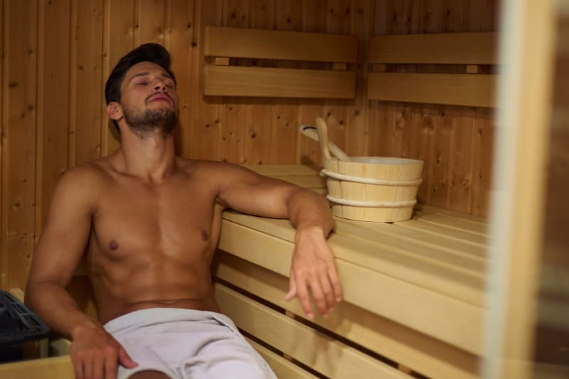 A man relaxing in a traditional sauna, potentially attempting to sweat out alcohol.