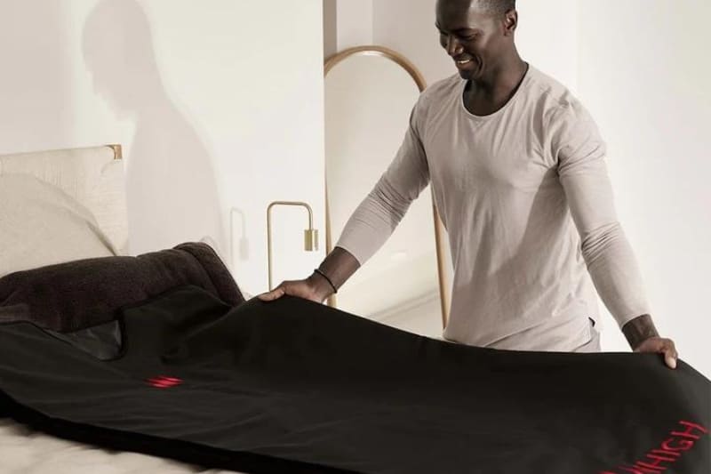 Man unfolding the MiHigh Infrared Sauna Blanket before a detox session.